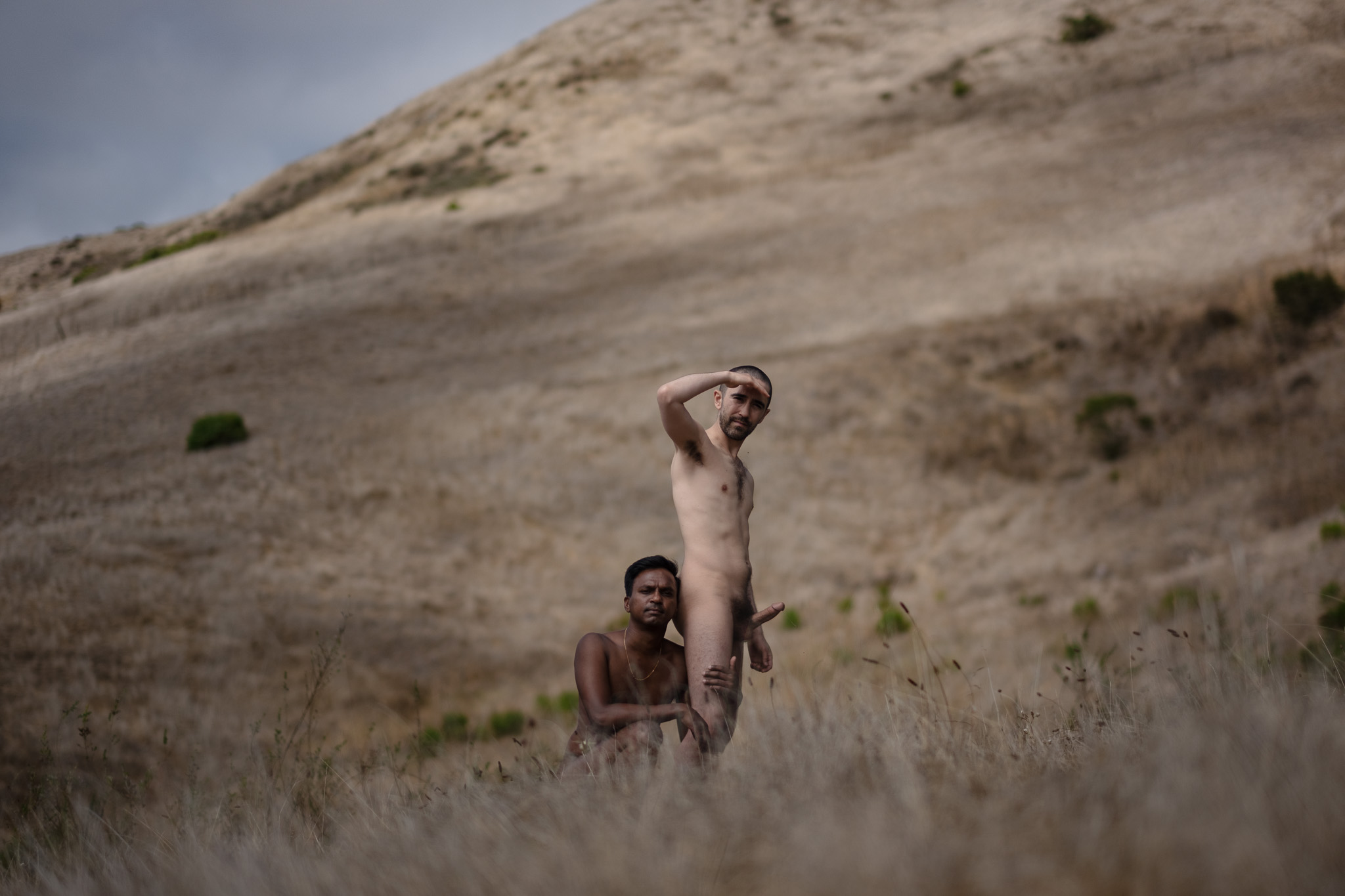 Nude self-portrait with another figure in a dry landscape